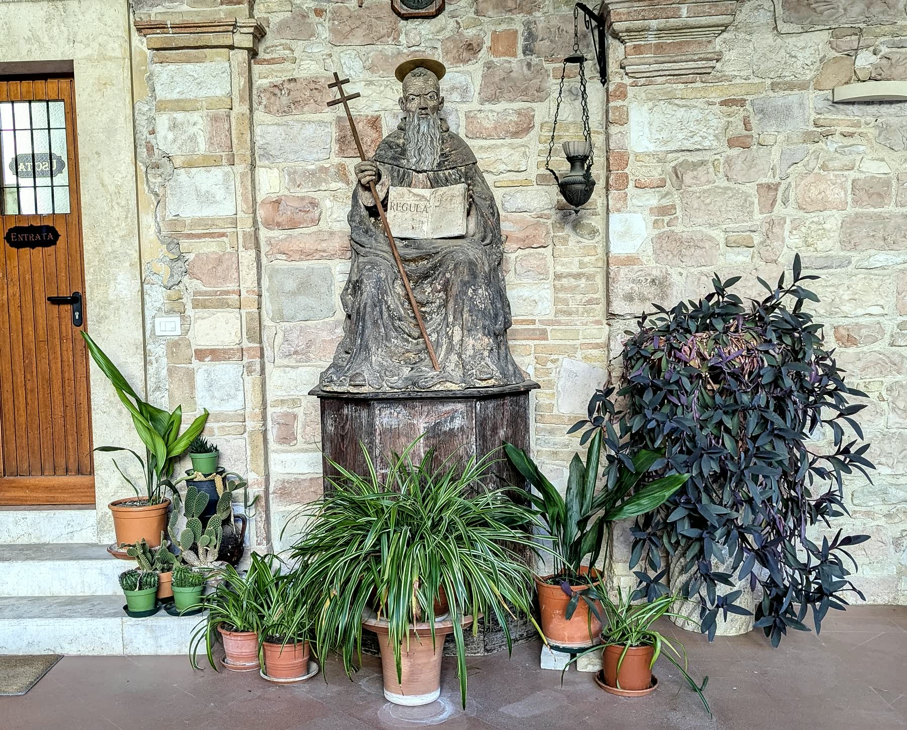 A carved saint holding the Rule among plants at the abbey