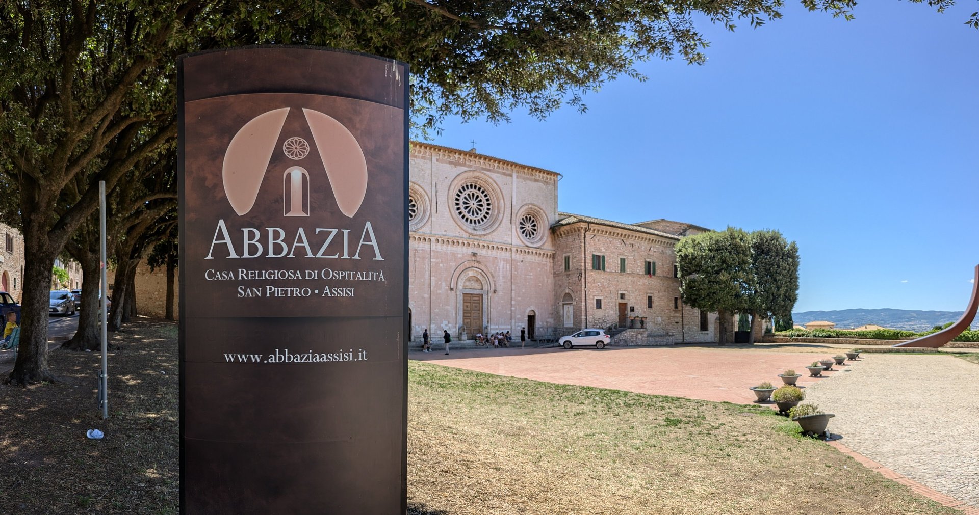 Abbazia San Pietro and its piazza beneath a clear blue Assisi sky