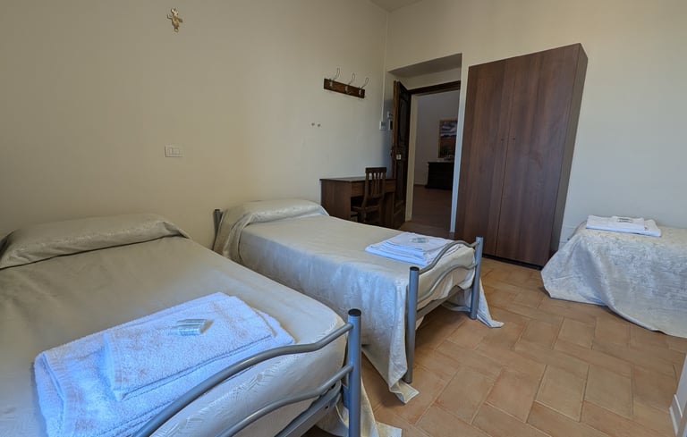A clean multi-bed room at Abbazia San Pietro